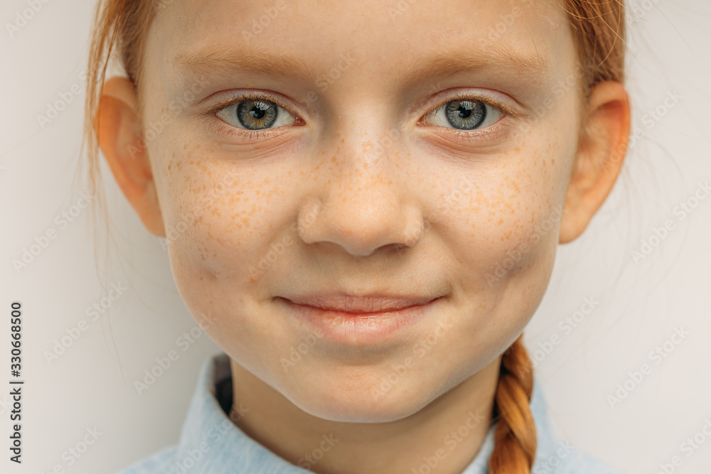 close-up portrait of beautiful smiling child girl with red hair, adorable  girl with freckles and unusual natural beauty look at camera and smile, she  is in good mood. isolated white background Stock-Foto