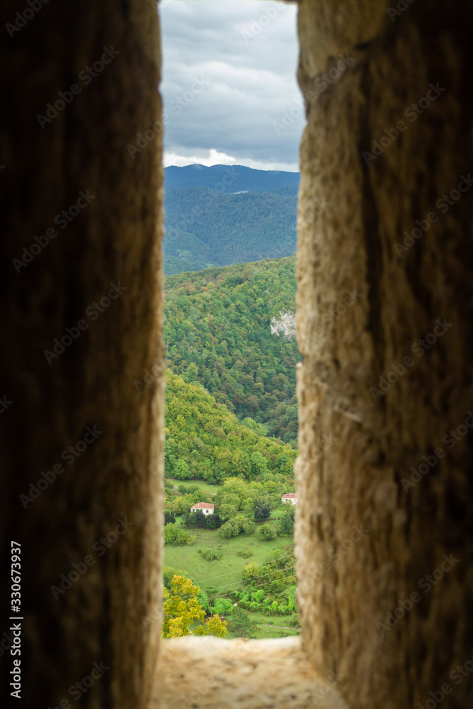 view of a green mountain valley through a narrow gap in the stone wall