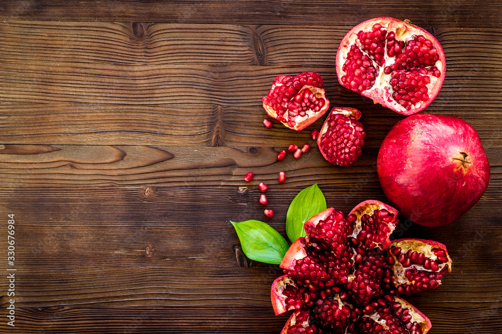 Ripe pomegranate fruit near leaf on dark wooden background top-down copy space Ripe pomegranate fruit near leaf on dark wooden background top-down copy space