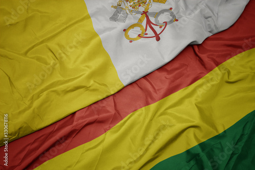 waving colorful flag of bolivia and national flag of vatican city.