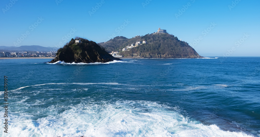 Ocean wave crashing on rock near the bay of La Concha and the island of Santa Clara . San Sebastian. Basque Country. Spain.