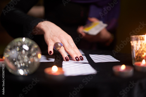 Fotografija Fortuneteller's hands with cards at table with candles, magic ball in dark room
