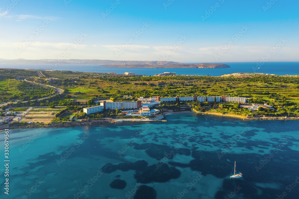Aerial panorama view of nature landscape in Mellieha city. Mediterranean blue sea, boat, hotel and forest. Malta 