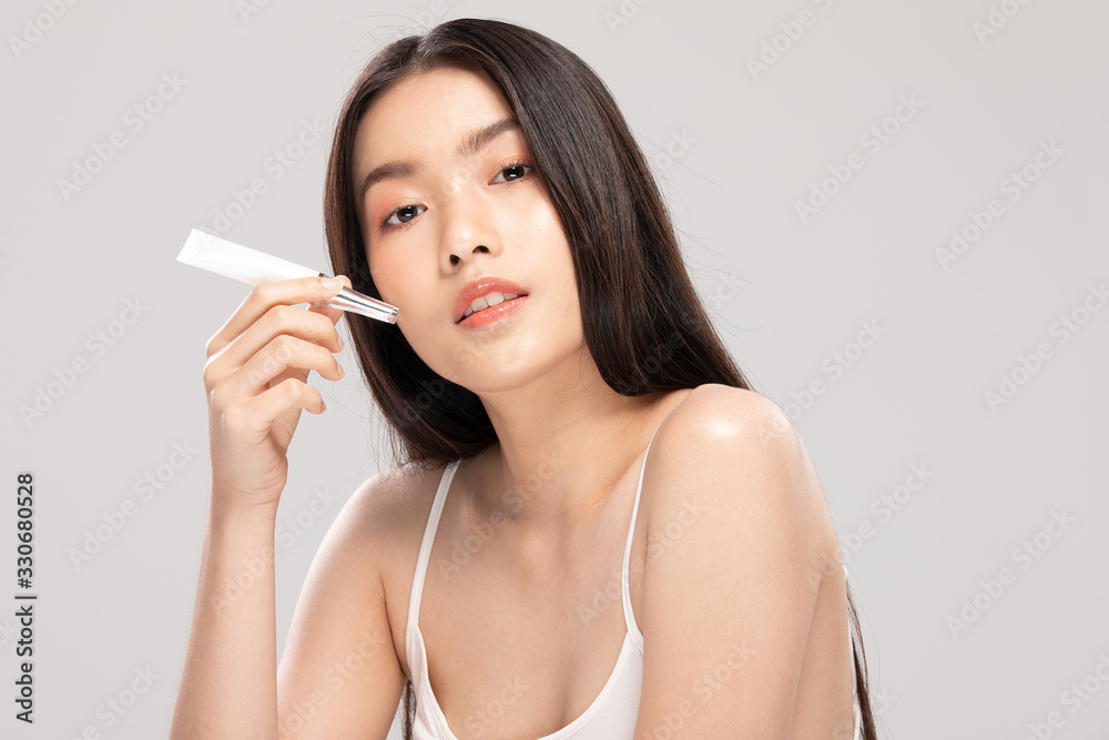Beautiful Young Asian Woman Holding luxury white clean tube smile feeling so happy and cheerful with healthy Clean and Fresh skin,isolated on gray background,Beauty Cosmetics Concept Beautiful Young Asian Woman Holding luxury white clean tube smile feeling so happy and cheerful with healthy Clean and Fresh skin,isolated on gray background,Beauty Cosmetics Concept