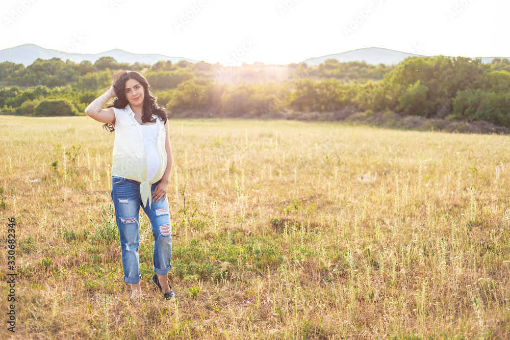 Pregnangt woman walking in the meadow with beautiful view