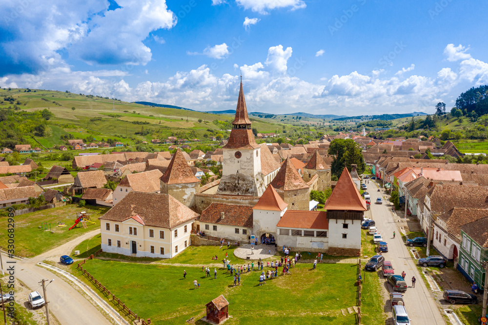 Aerial view of a saxon fortified Church in Transylvania, Romania, with blue sky and green grass Aerial view of a saxon fortified Church in Transylvania, Romania, with blue sky and green grass