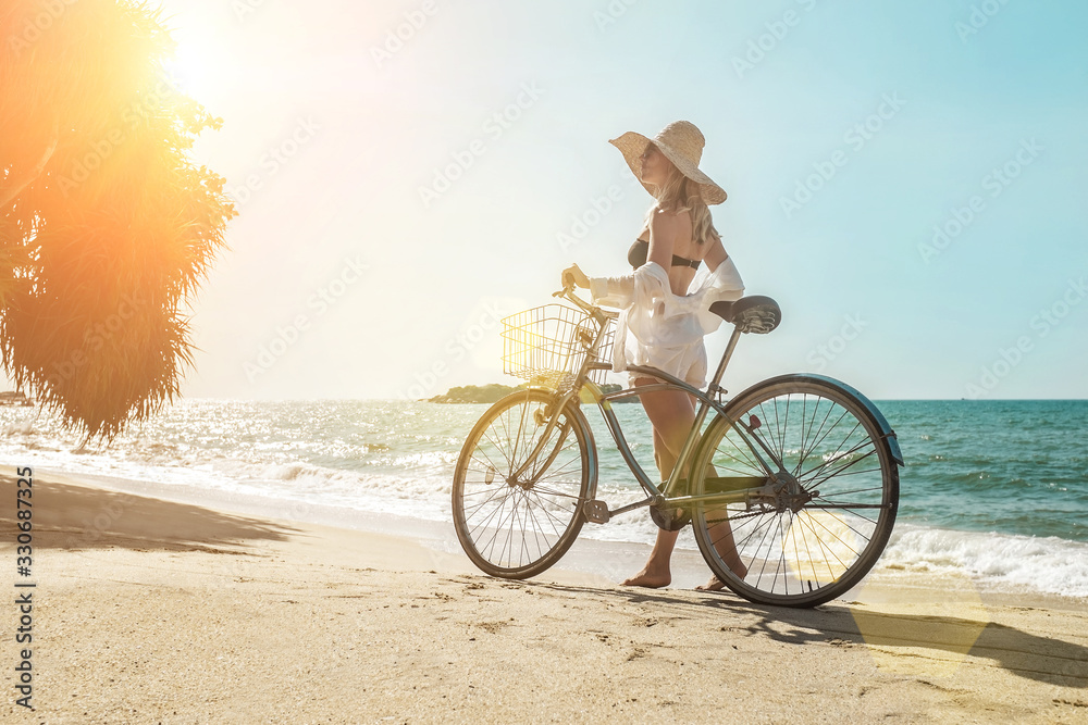 Fototapeta premium Happiness woman traveler with her bicycle rides on sea coastline