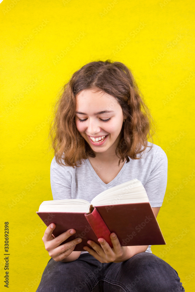 Curly beautiful girl reads a funny book and laughs. Home education Curly beautiful girl reads a funny book and laughs. Home education