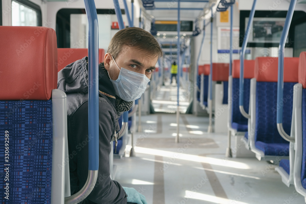Disease outbreak, coronavirus covid-19 pandemic, virus protection, quarantine. Portrait of wary adult man with medical protective mask and gloves on face inside empty public transport.