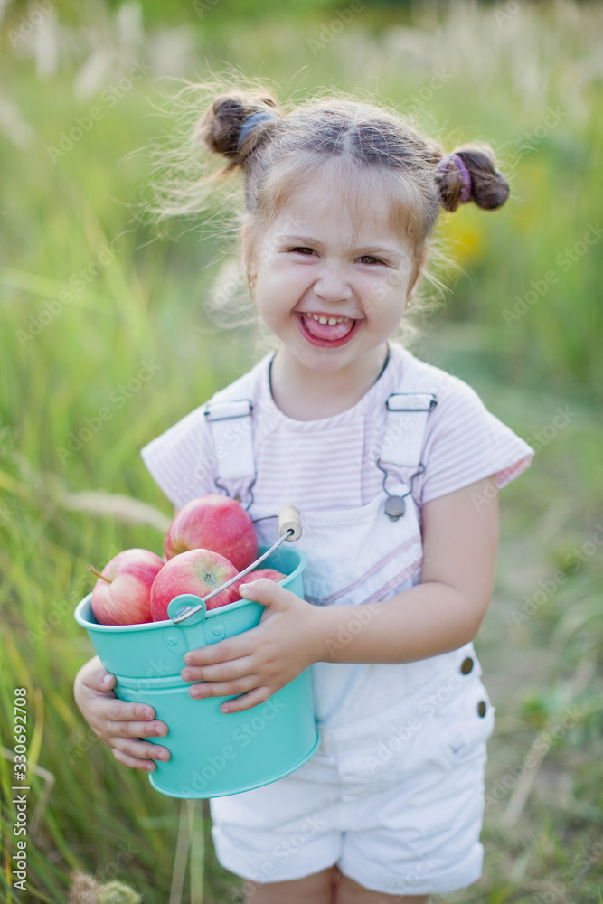Little caucasian girl with bucket of apples Little caucasian girl with bucket of apples