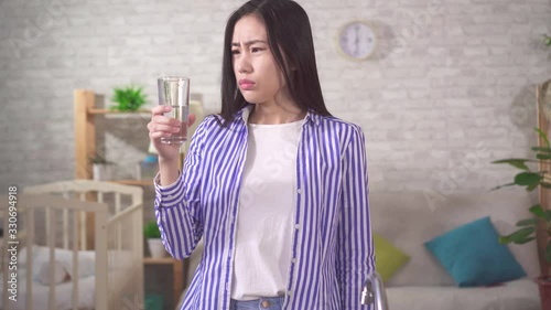 young asian woman drinks from a glass and is dissatisfied with the quality of water