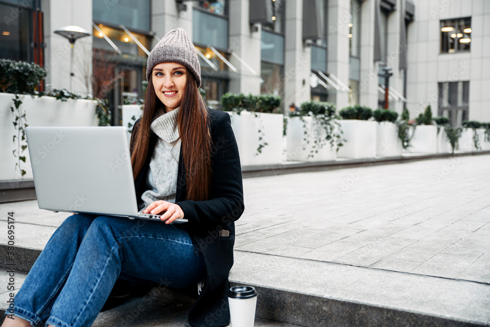 Woman with a laptop works sitting on a steps