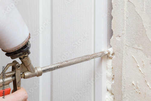 Konstfotografi Man hand using spray gun and filling gap with construction foam between new door and wall