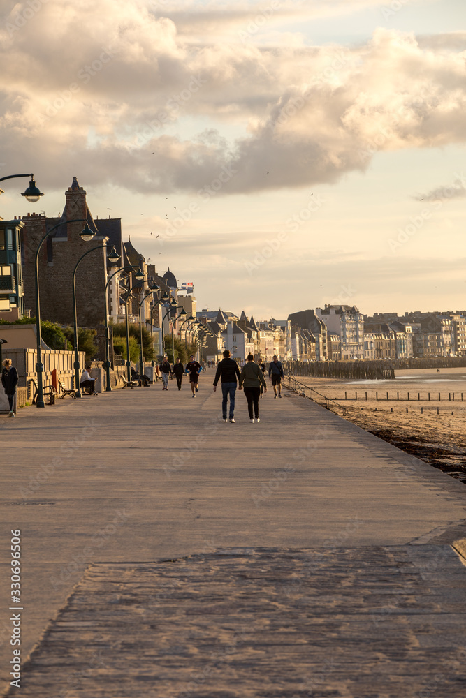  People walking along promenade at seafront in Saint Malo, Brittany, France