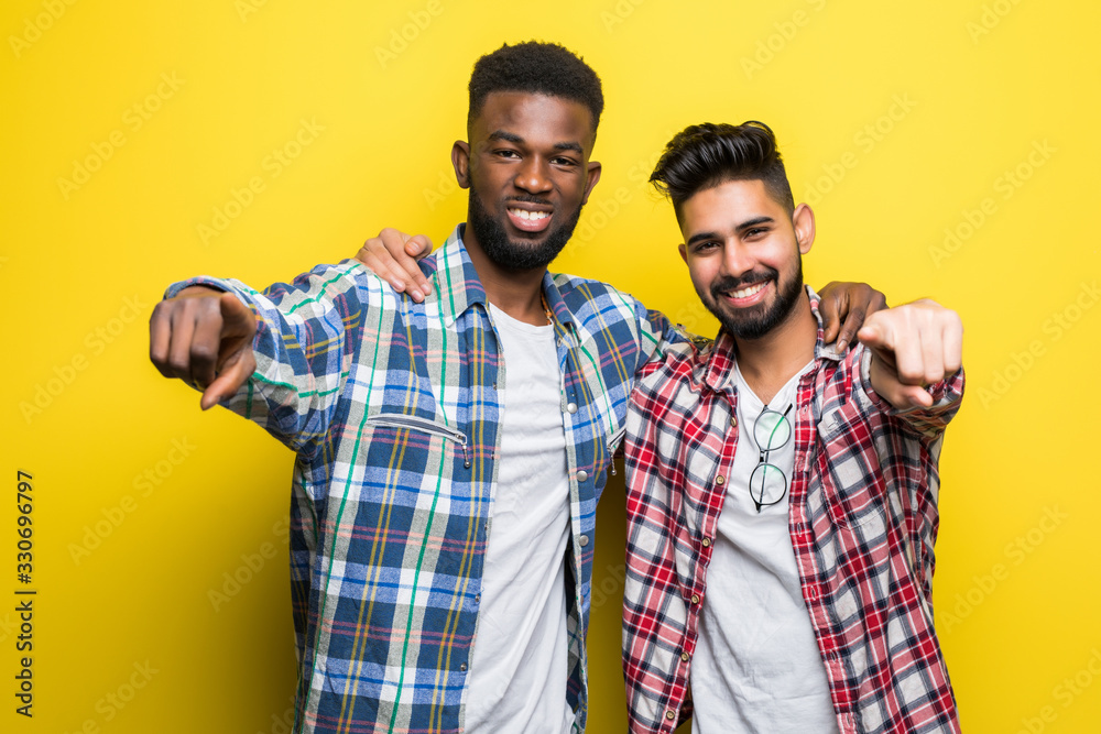 Two mixed race men pointed on you isolated on yellow background Two mixed race men pointed on you isolated on yellow background