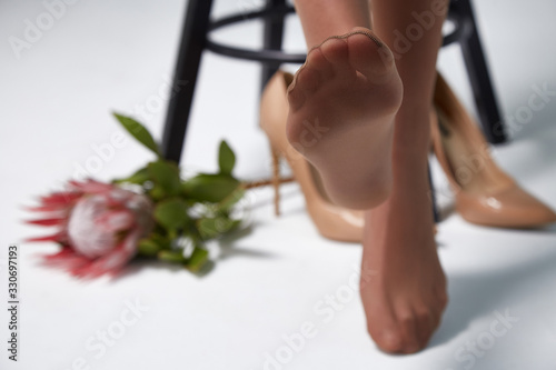 Part of woman body perfect shape legs feet skin tan wear stockings, nylons, pantyhose lingerie hosiery hose studio shot. on white background flower. photo