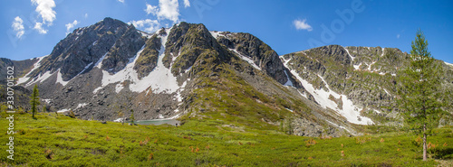 Spring in the mountains. Snow on the mountainside, the first green. Sunny day. Panoramic view. © Valerii