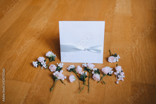 Beautiful white card, envelope, invitation for guests to a wedding with a ribbon and flowers on a wooden background. Photography, concept.