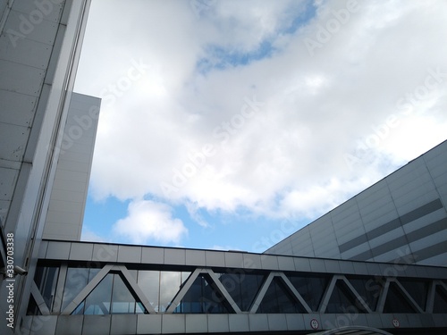 Architecture of a modern industrial and office building with a glass transition between two buildings with blue sky and white clouds