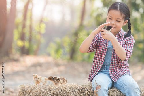 happy little girl with of small chickens sitting outdoor. portrait of an adorable little girl, preschool or school age, happy child holding a fluffy baby chicks with both hands and smiling..