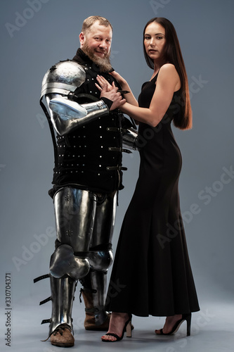 Beautiful girl in a black dress and knight in armor