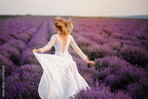 A young bride runs across a lavender field.
