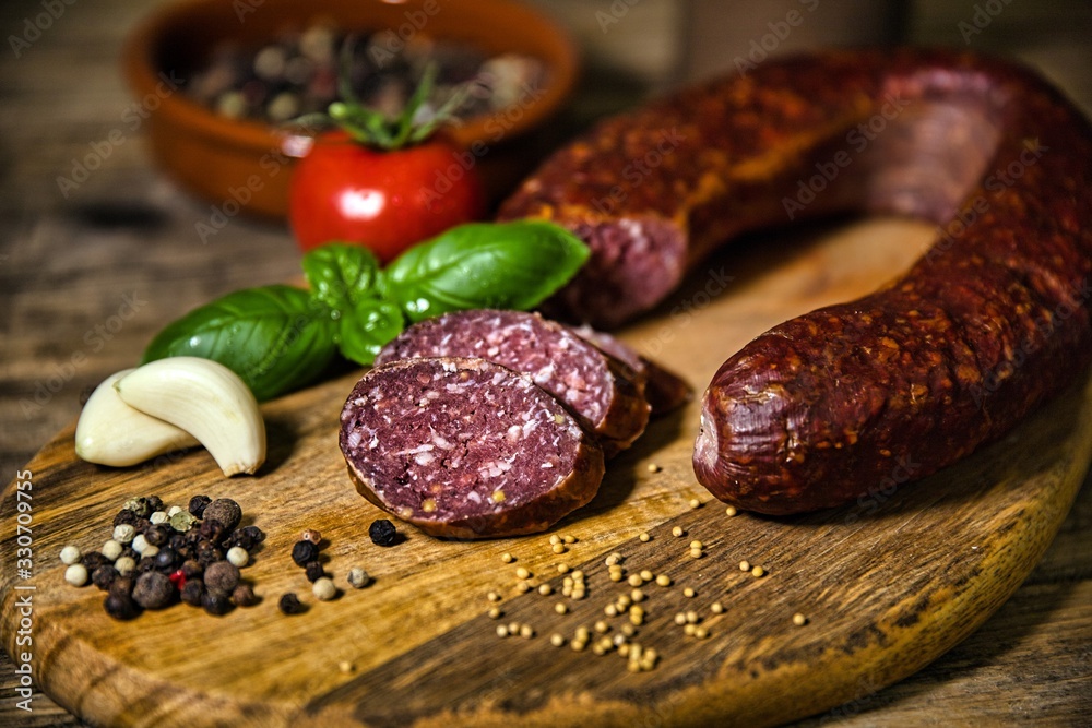 Smoked salami homemade with spices on a rustic wooden background Smoked salami homemade with spices on a rustic wooden background