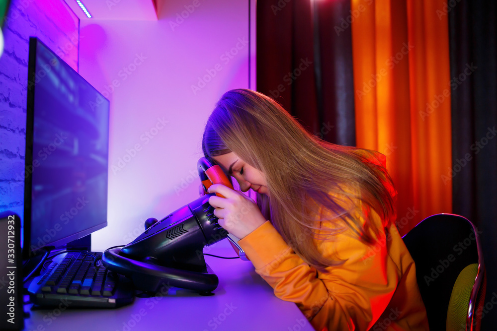 girl gamer playing racing on a computer. She uses a steering wheel. emotional play girl gamer playing racing on a computer. She uses a steering wheel. emotional play