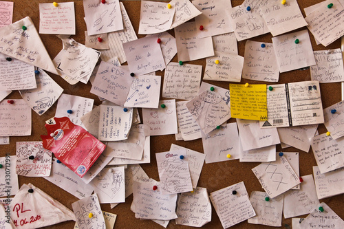 Post-it notes sticked chaotically on the wall - busy concept. in different languages