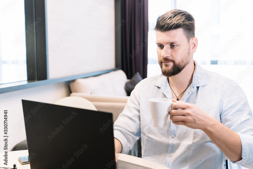Man working remotely with a laptop with a coffee Man working remotely with a laptop with a coffee