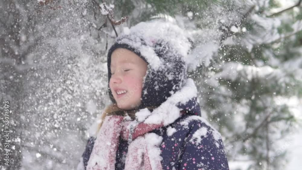 A close-up of a beautiful little girl in the winter forest during snowfall. A close-up of a beautiful little girl in the winter forest during snowfall.