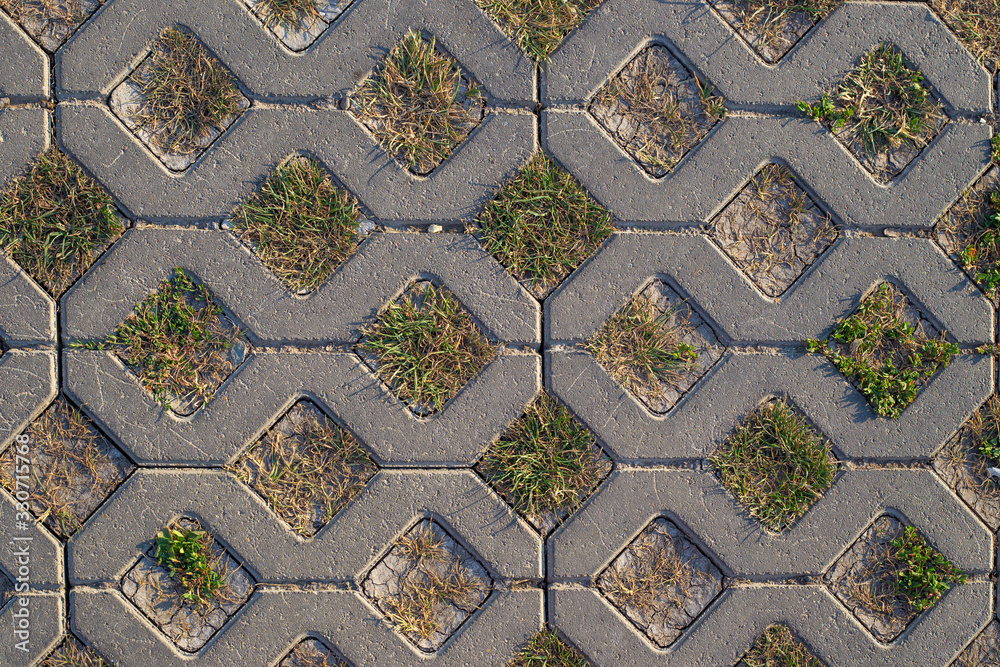 background of light paving stones in the form of rhombuses with sprouted grass