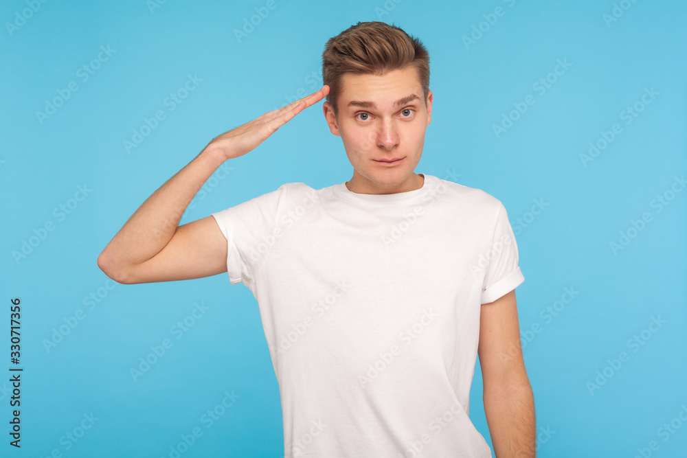 Yes, sir! Portrait of serious obedient man in t-shirt saluting with arm near temple and listening attentively to order, looking with respect, responsible expression. indoor studio shot blue background Yes, sir! Portrait of serious obedient man in t-shirt saluting with arm near temple and listening attentively to order, looking with respect, responsible expression. indoor studio shot blue background