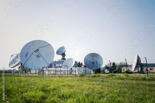 Barbed wire fence around satellite links center with telecommunication tower equipped with radar antennas, cybercrime and cybersecurity concept