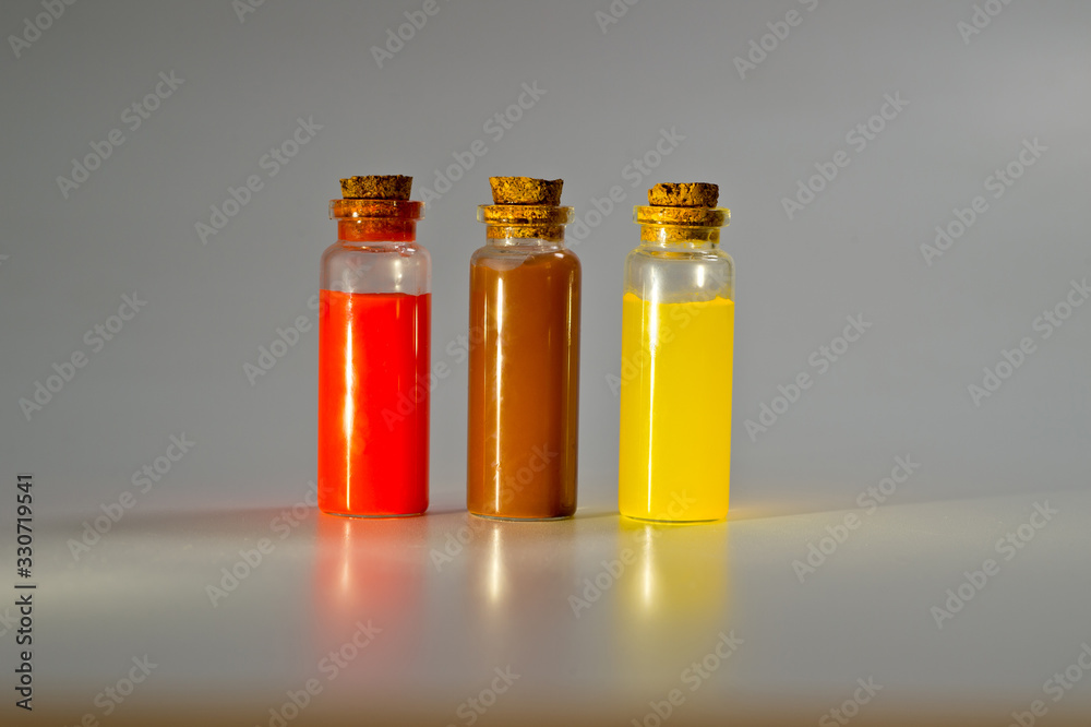 Three glass corked bottles filled with liquid. Background for science and medicine. Virus vaccine. Three glass corked bottles filled with liquid. Background for science and medicine. Virus vaccine.