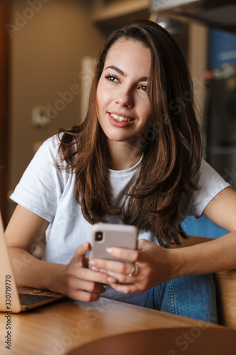 Optimistic woman indoors at home using mobile phone.