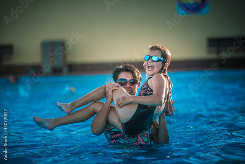 Summer camp, szczęśliwa mama z córką pływa i bawi się na basenie w wodzie latem