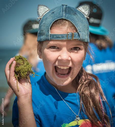 Summer camp. Szczęśliw i uśmiechnięta dziewczynka spędza wakacje nad morzem razem z innymi dziećmi na kolonii