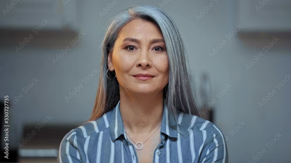 senior asian woman with grey hair looking at camera