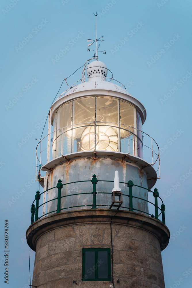 Close up of lighthouse beacon lighting up at sunset and blue background