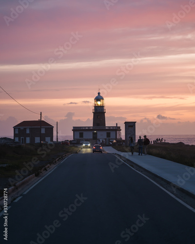 Beautiful lighthouse at the end of long road at sunset in Galicia, Spain