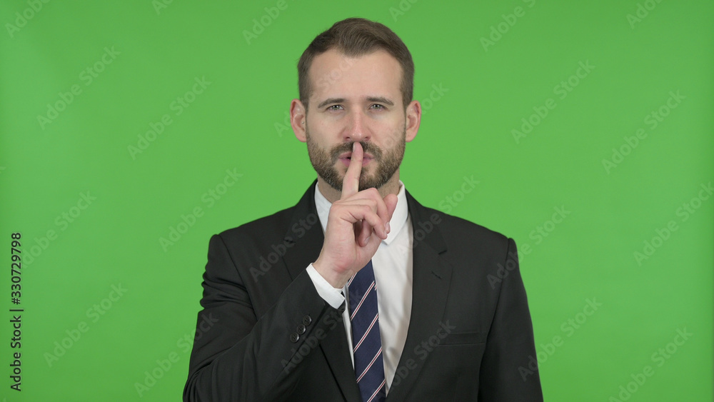 The Young Businessman putting his Finger on Lips against Chroma Key The Young Businessman putting his Finger on Lips against Chroma Key