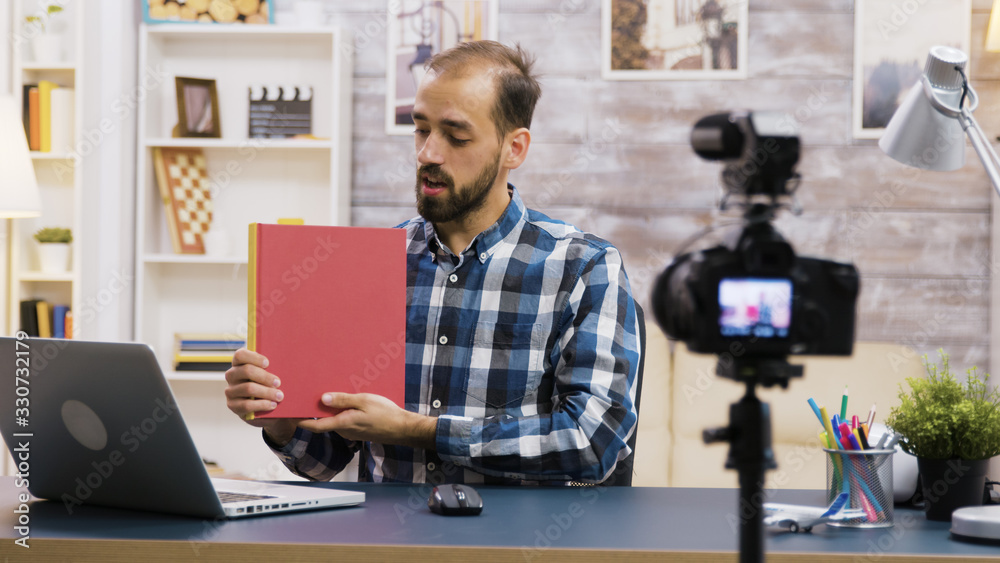 Famous young vlogger recording a review of a book Famous young vlogger recording a review of a book