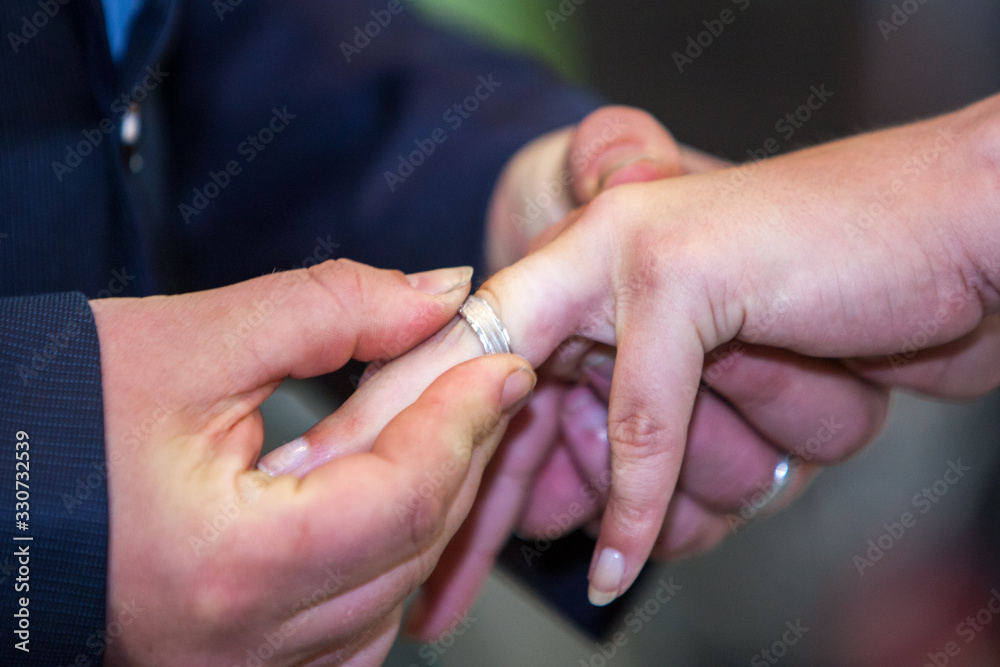 Fototapeta premium An unrecognizable bride and groom exchanging of the Wedding Rings in church during the christian wedding ceremony 
