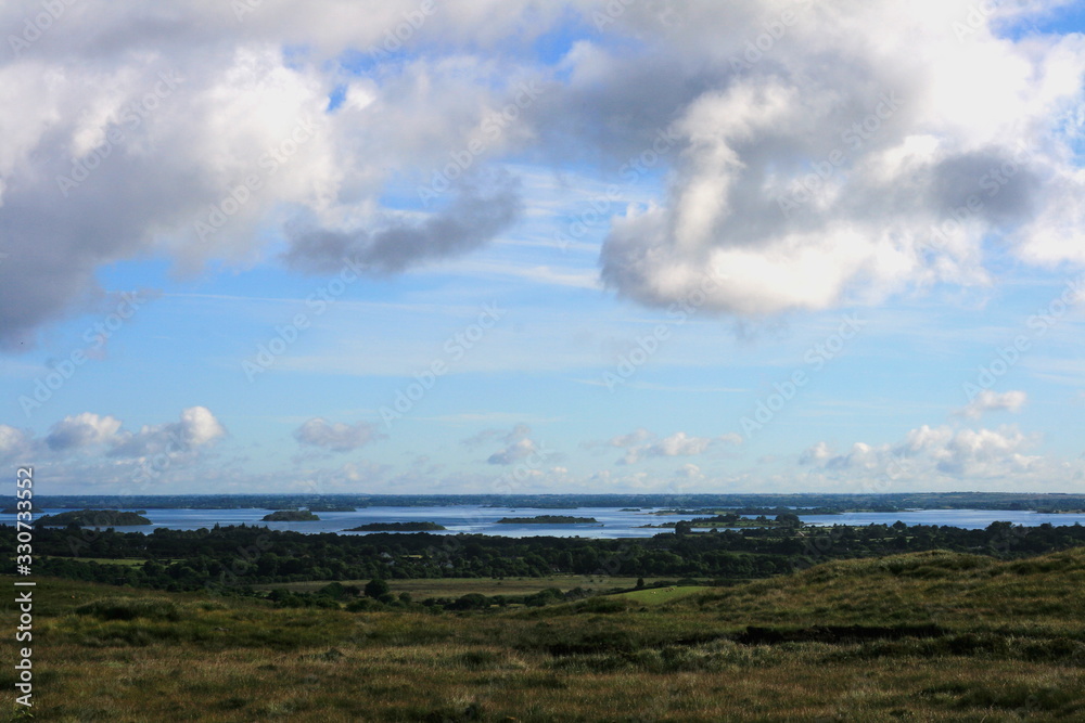 wide landscape view over rolling green hills, villages and lake from Connemara, Galway, Ireland, Lough Corrib in background
