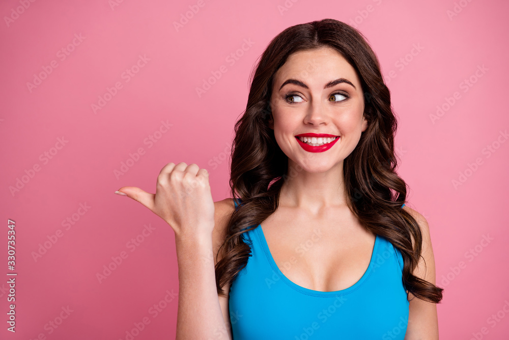 Closeup photo of crazy funny curly lady direct thumb finger side empty space show low prices advert banner sale offer wear casual blue singlet isolated pink color background Closeup photo of crazy funny curly lady direct thumb finger side empty space show low prices advert banner sale offer wear casual blue singlet isolated pink color background