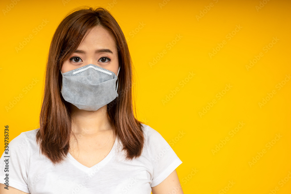 Asian woman wearing hygienic mask to protect virus, COVID 19 or Colona Virus infection and dust PM 2.5 pollution isolate on yellow background Asian woman wearing hygienic mask to protect virus, COVID 19 or Colona Virus infection and dust PM 2.5 pollution isolate on yellow background