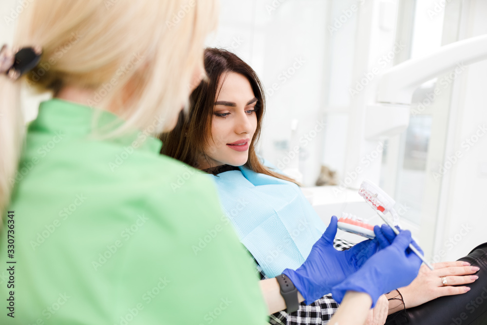 Dentist doctor shows the patient a jaw model and talks about the upcoming treatment. Dentist doctor shows the patient a jaw model and talks about the upcoming treatment.