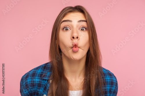 Quadro em tela Closeup of amazed childish cute girl in checkered shirt standing with pout lips making fish face, having fun, showing surprised silly expression