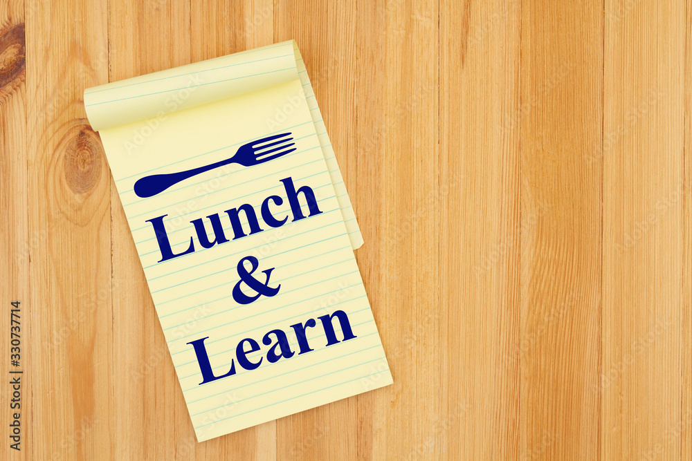 Lunch and Learn message with a fork on a notepad on wood desk Lunch and Learn message with a fork on a notepad on wood desk